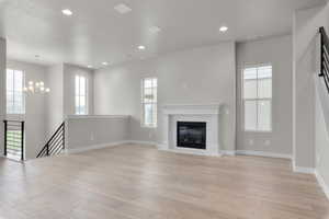 Unfurnished living room featuring an inviting chandelier and light wood-type flooring