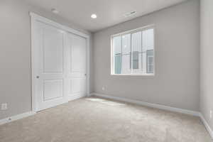 Unfurnished bedroom with light colored carpet, a closet, and multiple windows