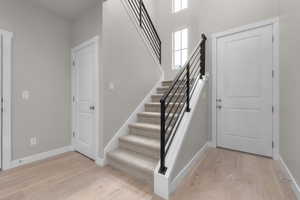 Staircase with wood-type flooring and a high ceiling