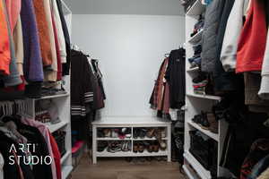 Walk in closet with wood-type flooring