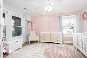 Bedroom with ceiling fan, light hardwood / wood-style flooring, radiator, and a crib