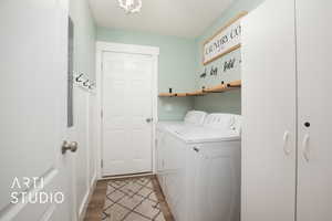 Clothes washing area with washing machine and dryer and dark hardwood / wood-style flooring