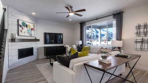 Living room featuring ceiling fan, a textured ceiling, a tile fireplace, and light wood-type flooring