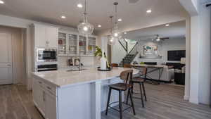 Kitchen with built in microwave, hanging light fixtures, oven, and white cabinets