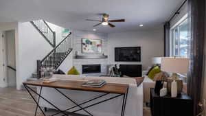 Living room featuring ceiling fan, a fireplace, and light hardwood / wood-style floors