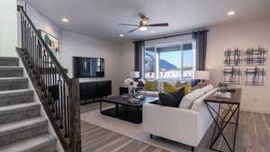 Living room with ceiling fan, wood-type flooring, and a textured ceiling