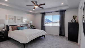 Bedroom featuring ceiling fan, a textured ceiling, a mountain view, light colored carpet, and a raised ceiling