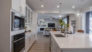 Kitchen featuring stainless steel appliances, pendant lighting, a center island with sink, and white cabinets