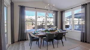 Dining space featuring light hardwood / wood-style flooring, vaulted ceiling, and an inviting chandelier