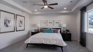 Bedroom featuring dark carpet, a raised ceiling, and ceiling fan