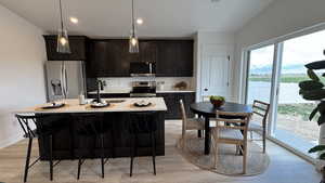 Kitchen with a kitchen breakfast bar, a sink, light wood-type flooring, stainless steel appliances, and light countertops