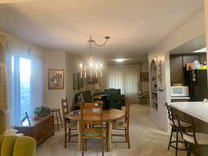 Carpeted dining space with a notable chandelier and a textured ceiling