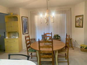 Dining area with light carpet, a textured ceiling, and an inviting chandelier