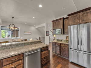 Kitchen with appliances with stainless steel finishes, dark wood-style floors, light stone counters, a chandelier, and recessed lighting