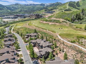 Aerial overview of property's location featuring a mountain backdrop, a local golf course, and nearby suburban area