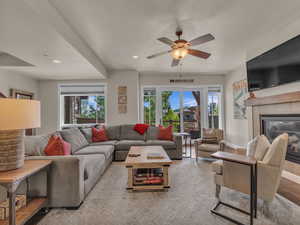 Living room with plenty of natural light, baseboards, ceiling fan, a tiled fireplace, and recessed lighting