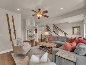 Living room with ceiling fan, baseboards, dark wood finished floors, stairs, and recessed lighting