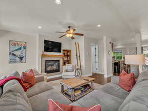 Living room with wood finished floors, a tiled fireplace, recessed lighting, baseboards, and a ceiling fan