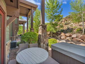 View of patio with a hot tub, central AC, and outdoor dining area