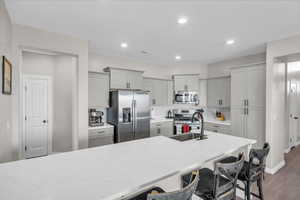 Kitchen featuring light stone countertops, appliances with stainless steel finishes, gray cabinetry, and decorative backsplash