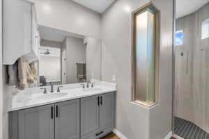 Bathroom featuring ceiling fan, tiled shower, and vanity