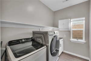 Clothes washing area featuring cabinets, hardwood / wood-style flooring, and washer and dryer