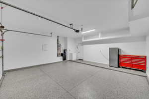 Garage featuring a garage door opener, gas water heater, stainless steel fridge, and washer and clothes dryer