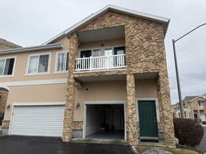 View of front of home featuring a garage and a balcony