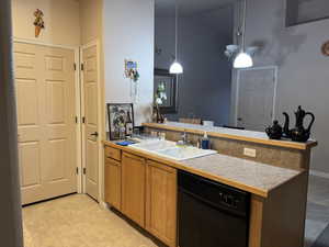 Kitchen featuring hanging light fixtures, sink, dishwasher, and light tile patterned flooring