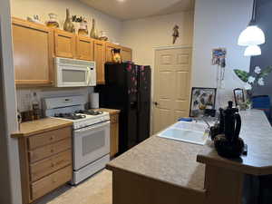 Kitchen featuring pendant lighting, white appliances, and sink