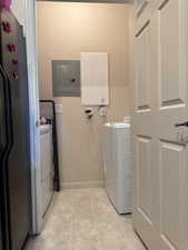 Washroom featuring electric panel, washing machine and clothes dryer, and light tile patterned floors