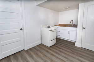 Kitchen with white cabinetry, sink, dark wood-type flooring, and white range with electric stovetop