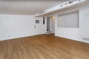 Empty room featuring rail lighting and light wood-type flooring