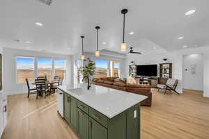 Kitchen with pendant lighting, sink, an island with sink, and green cabinetry