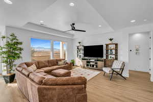 Living room featuring ceiling fan, a tray ceiling, and light hardwood / wood-style floors