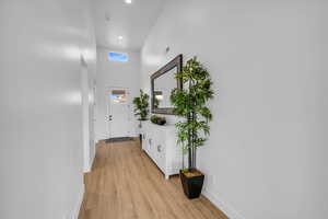 Corridor with a towering ceiling and light hardwood / wood-style floors