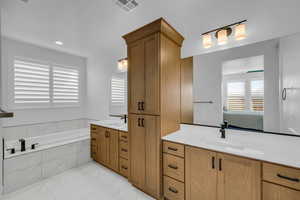 Bathroom featuring vanity and tiled bath