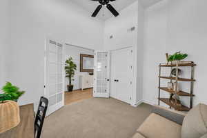 Interior space featuring french doors, ceiling fan, light carpet, and a towering ceiling