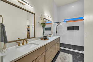 Bathroom with tiled shower, vanity, and tile patterned flooring