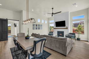 Dining room featuring a fireplace, a barn door, ceiling fan, and light wood-type flooring