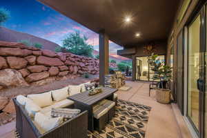 Patio terrace at dusk with an outdoor kitchen, a grill, and outdoor lounge area