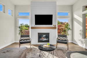 Living room with light hardwood / wood-style flooring, a fireplace, and a healthy amount of sunlight