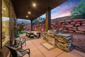 Patio terrace at dusk featuring an outdoor hangout area, grilling area, and an outdoor kitchen