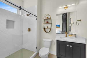 Bathroom featuring vanity, a shower with door, and toilet