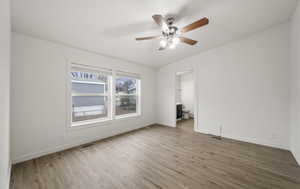 Empty room with hardwood / wood-style floors and ceiling fan