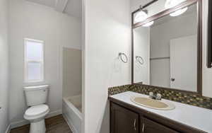 Bathroom with vanity, wood-type flooring, tasteful backsplash, and toilet