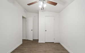 Unfurnished bedroom featuring dark wood-type flooring and ceiling fan