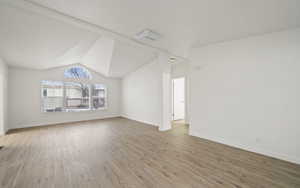 Unfurnished living room featuring vaulted ceiling and hardwood / wood-style floors