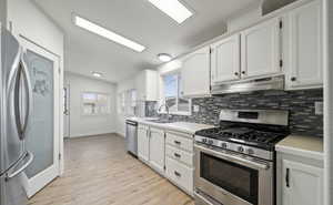 Kitchen featuring white cabinetry, appliances with stainless steel finishes, sink, and lofted ceiling