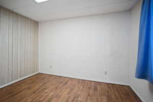 Spare room with hardwood / wood-style flooring, a paneled ceiling, and wood walls